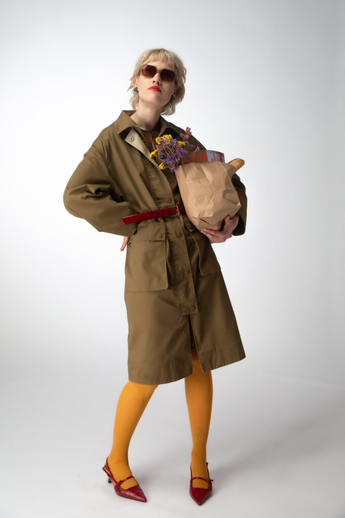 HCommercial fashion photography by Łukasz Zając, full-body shot of a blonde model in a trench coat holding a paper bag, Poland
