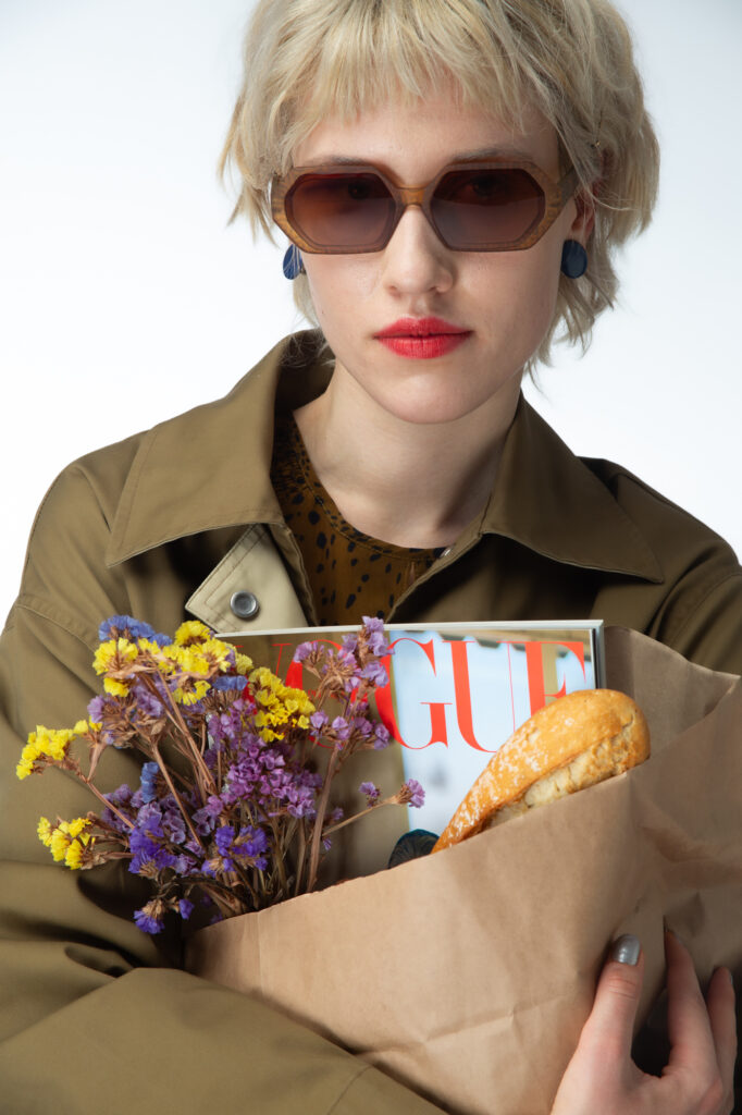 Commercial fashion photography by Łukasz Zając, portrait of a blonde model with sunglasses and a paper bag of flowers and magazine, Poland