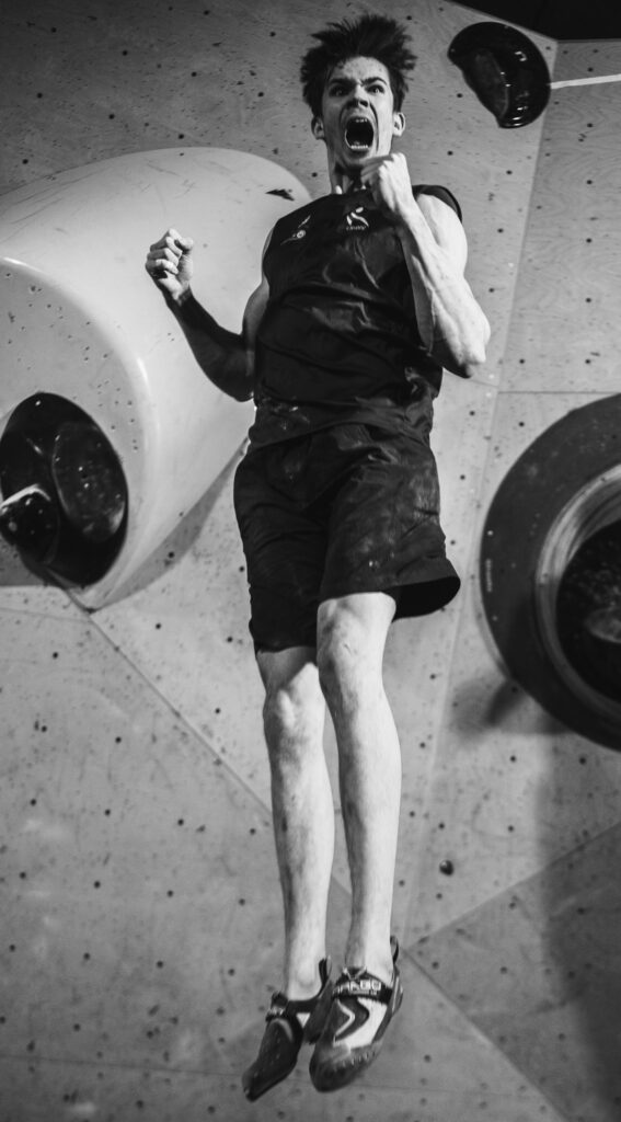 Sports and action photography by Łukasz Zając, black and white shot of an athlete jumping or suspended in the air near a climbing wall, Poland
