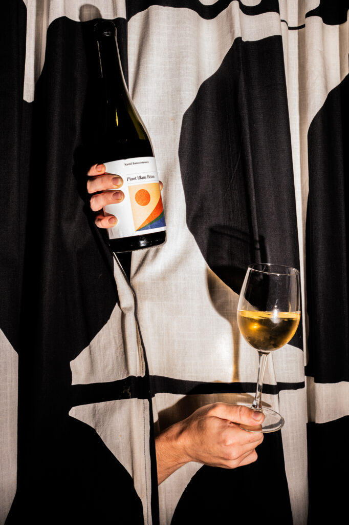 Commercial beverage photography by Łukasz Zając, pouring white wine from a bottle into a glass, Poland