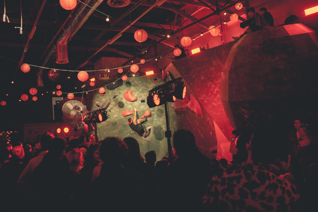 Sports and event photography by Łukasz Zając, atmospheric shot of an indoor climbing event lit by red lights and hanging lanterns, Kraków, Poland