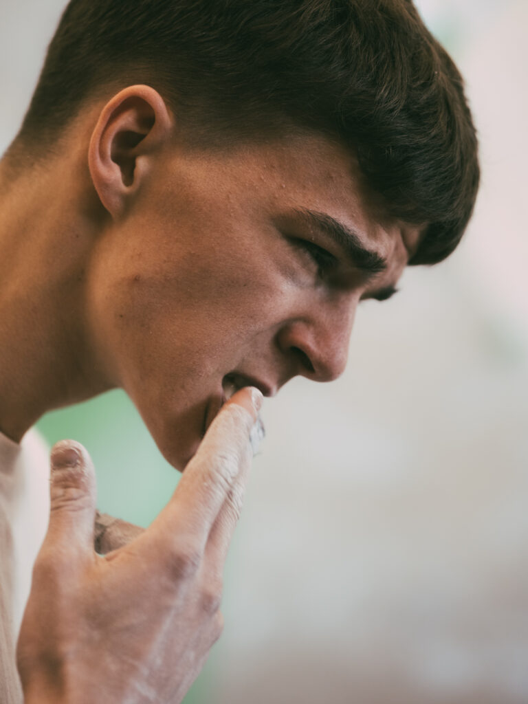 Portrait photography by Łukasz Zając, close-up side profile of a young man touching his chin in a thoughtful expression, Kraków, Poland