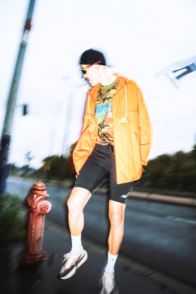 Street and fashion photography by Łukasz Zając, full-length shot of a person in an orange jacket posing on a city street, Kraków, Poland