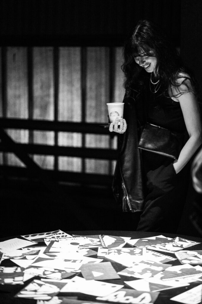 Art exhibition photography by Łukasz Zając, black and white portrait of a person holding a cup near an art installation, Poland
