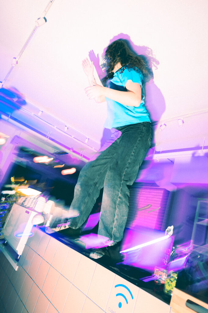 Lifestyle photography by Łukasz Zając, woman dancing energetically on an elevated platform during an indoor event, Poland