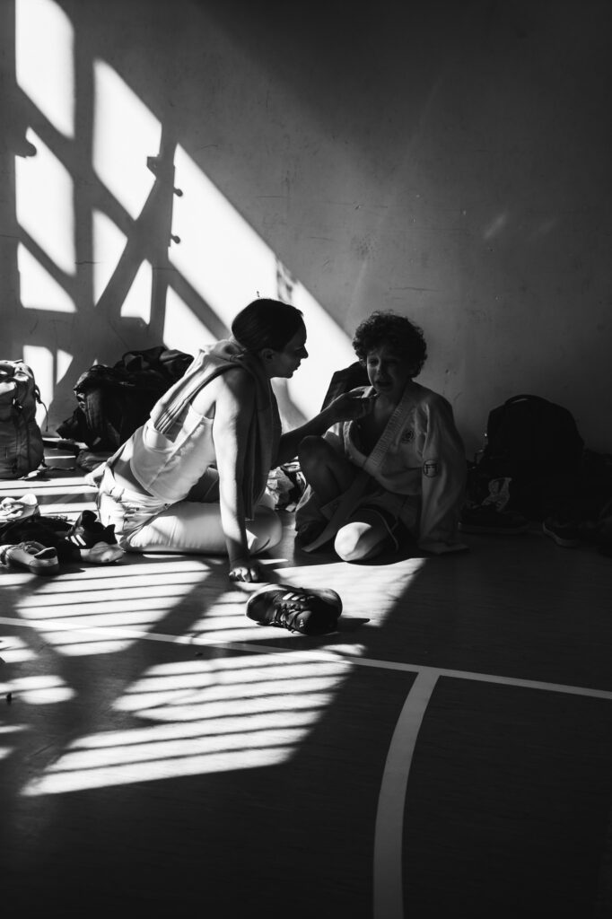 Sports and lifestyle photography by Łukasz Zając, black and white shot of athletes resting indoors with dramatic light and shadow patterns, Poland