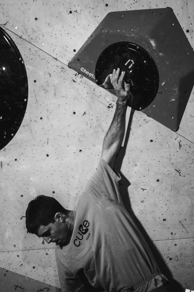 Sports and action photography by Łukasz Zając, black and white close-up of a climber hanging from a single hold on a training wall, Poland