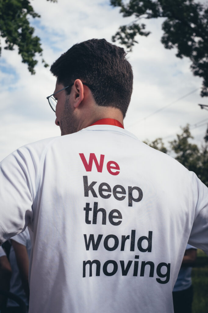 A person wearing a white t-shirt with the text "We keep the world moving" printed on the back.