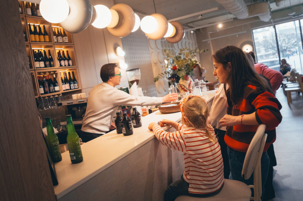 Lifestyle photography by Łukasz Zając, A cozy gathering or wine-tasting scene inside a bar or restaurant with people seated at the counter under modern lighting.