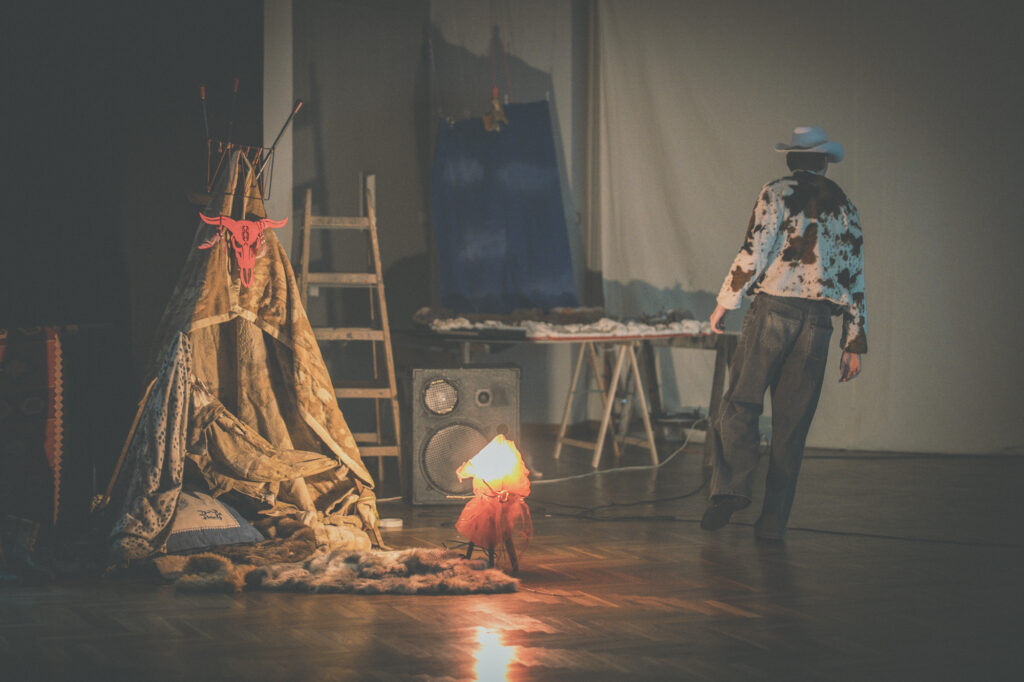 Theater and stage performance photography by Łukasz Zając, artistic setup featuring a makeshift tent structure, ladder, and props on a stage, Kraków, Poland