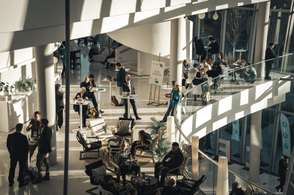 Corporate event and architectural photography by Łukasz Zając, high-angle view of people networking and socializing in the sunlit multi-level lobby of the ICE Kraków Congress Centre in Kraków, Poland