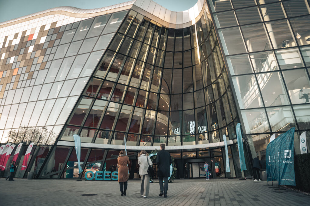 Event and architectural photography by Łukasz Zając, exterior wide shot of people walking toward the modern glass facade of the ICE Kraków Congress Centre in Kraków, Poland