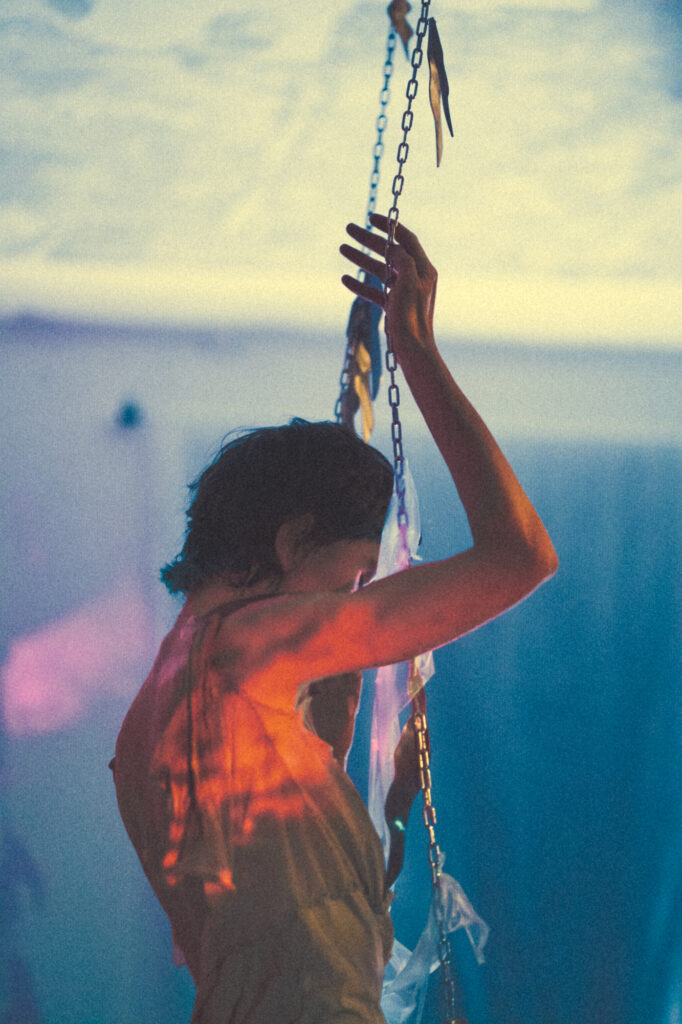 Art performance photography by Łukasz Zając, creative color shot of a performer interacting with vertical ropes and textile structures, Poland