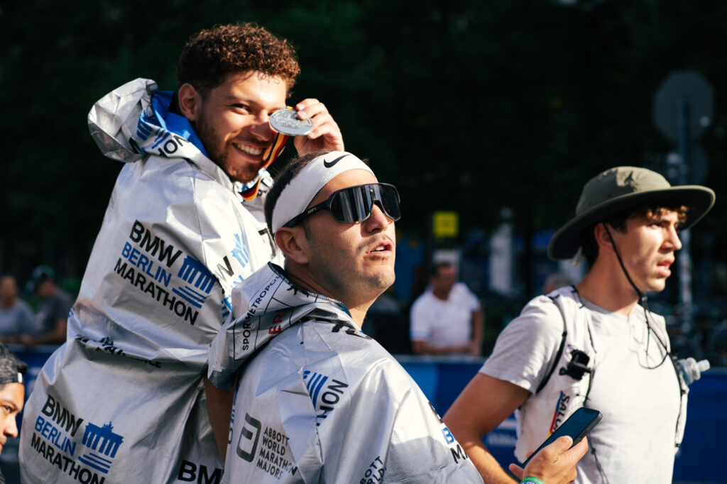 Sports and event photography by Łukasz Zając, portrait of runners celebrating after a race event, wearing medals and BMW Berlin Marathon jackets, Poland