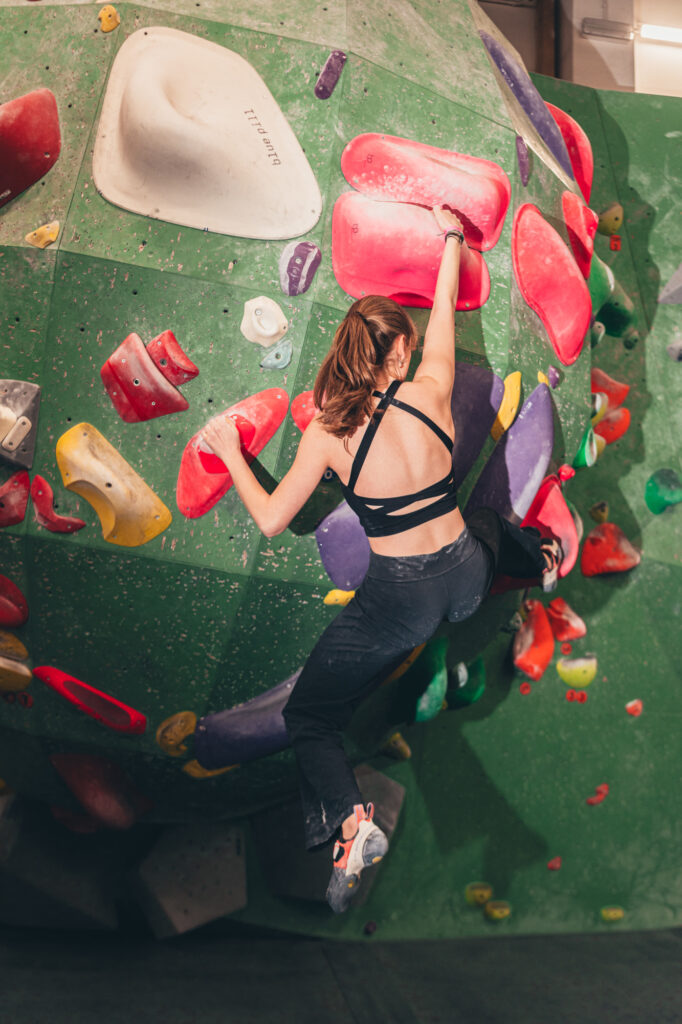 Sports photography by Łukasz Zając, vertical color shot of a climber navigating colorful holds on an indoor bouldering wall, Kraków, Poland