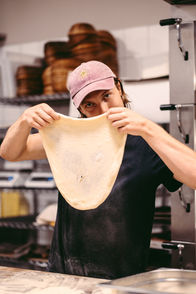Lifestyle and culinary photography by Łukasz Zając, chef stretching out dough in a professional kitchen or pizzeria, Kraków, Poland