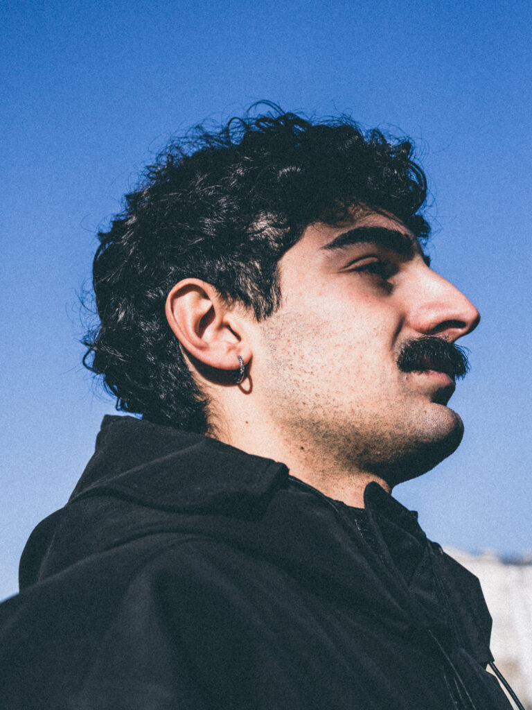 Editorial portrait photography by Łukasz Zając, clean and modern portrait of a man with a mustache posing in a dark sweatshirt, Krakow, Poland
