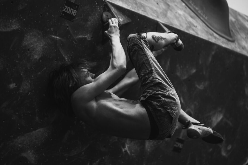 Sports and action photography by Łukasz Zając, black and white dynamic shot of a climber scaling an indoor bouldering wall, Kraków, Poland
