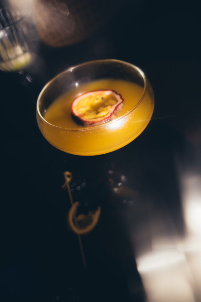Commercial beverage photography by Łukasz Zając, cocktail in a coupe glass garnished with a slice of passion fruit, Kraków, Poland