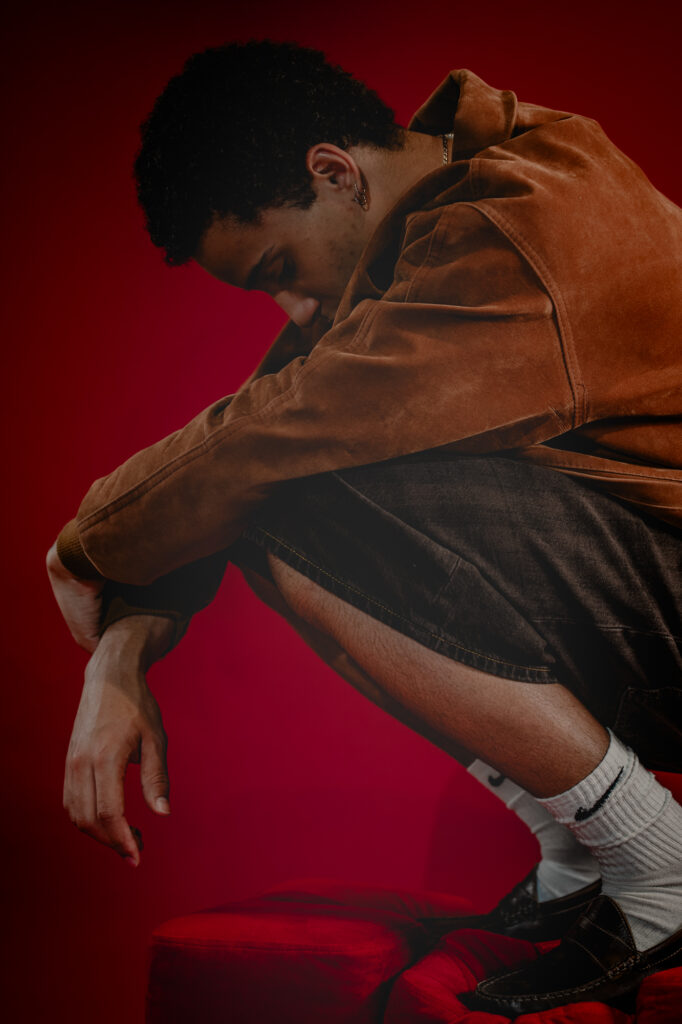 Commercial fashion photography by Łukasz Zając, model in brown streetwear jacket under dramatic red lighting, Krakow, Poland