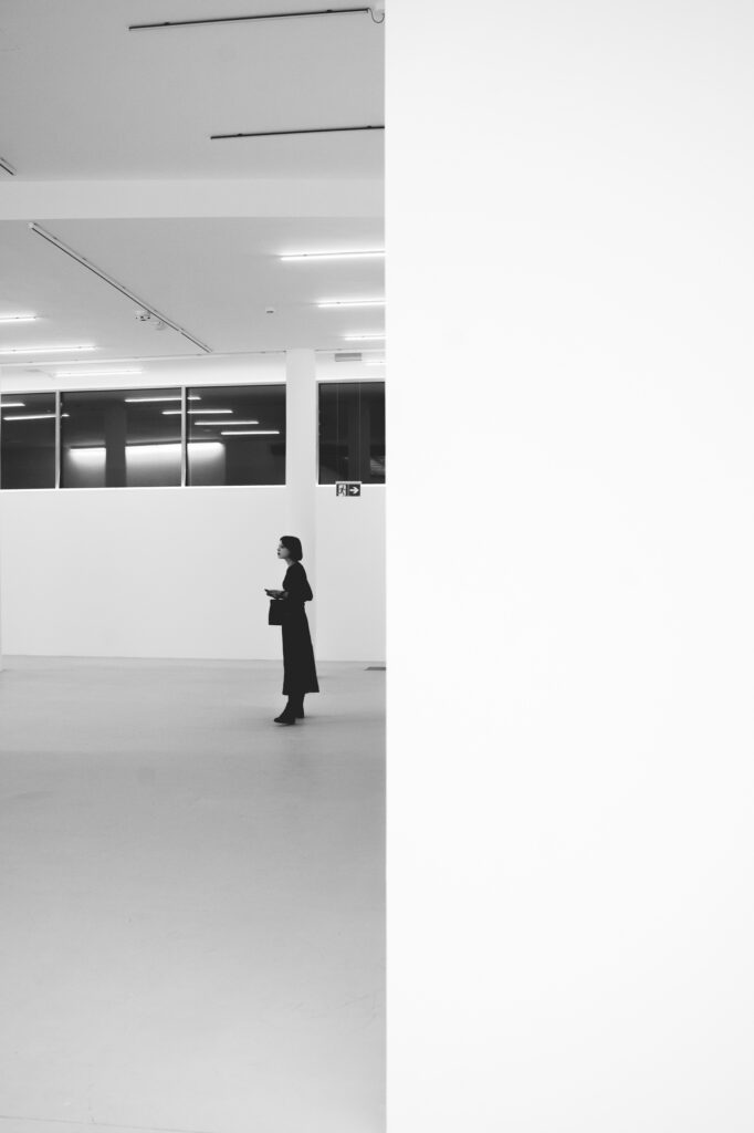 Minimalist art gallery photography by Łukasz Zając, wide angle view of a person standing in a bright, modern exhibition space, Poland