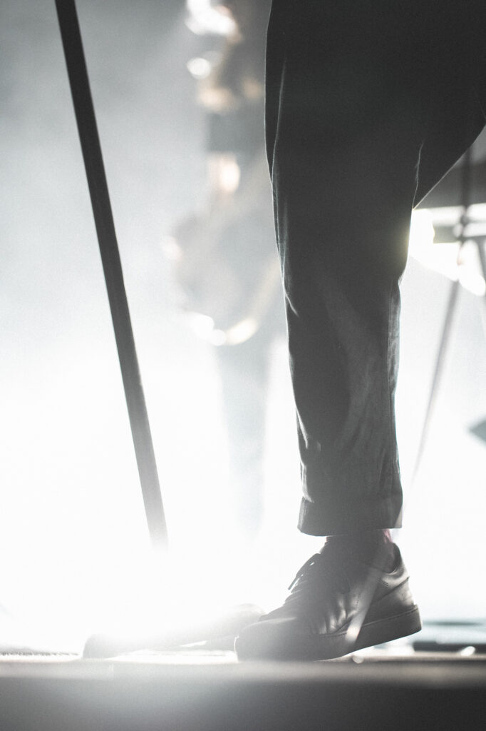 Culture and events concert photography by Łukasz Zając, low-angle shot of a performer's legs and shoes on a bright stage, Poland