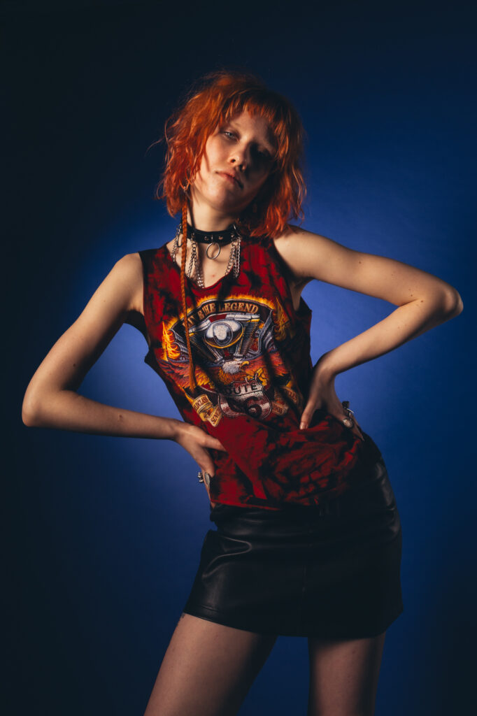 Commercial fashion photography by Łukasz Zając, model with red hair wearing dark top against blue lighting, Poland